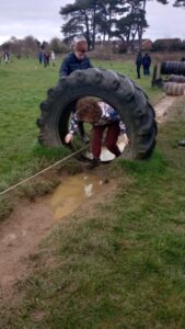 A young learning climbing through a tyre obstacle of an assault course
