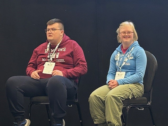 Two learners sitting down on stage at the conference