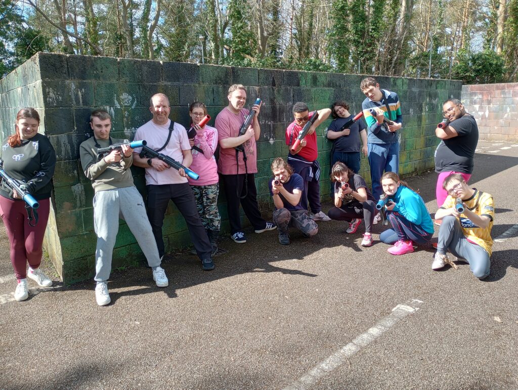 A group of people posing with paintball weapons