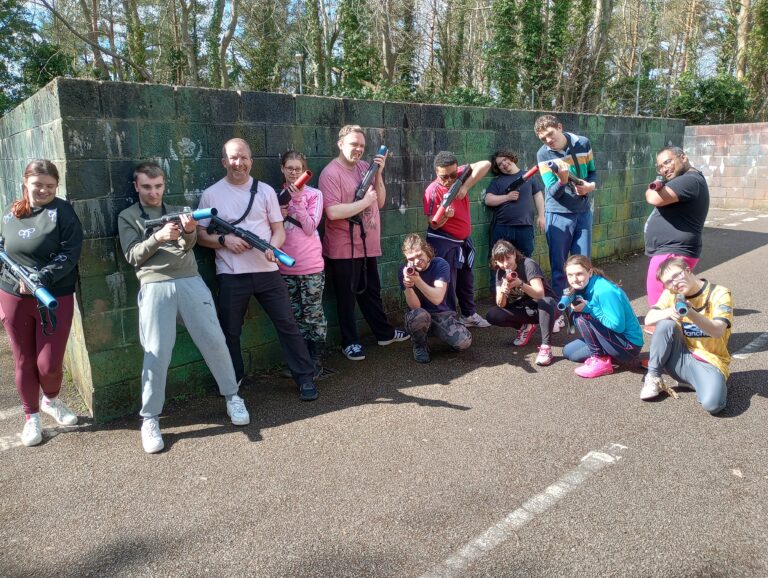 A group of people posing with paintball weapons