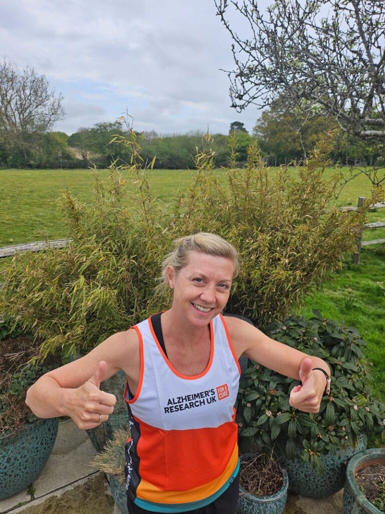 A woman with both thumbs up wearing a running outfit