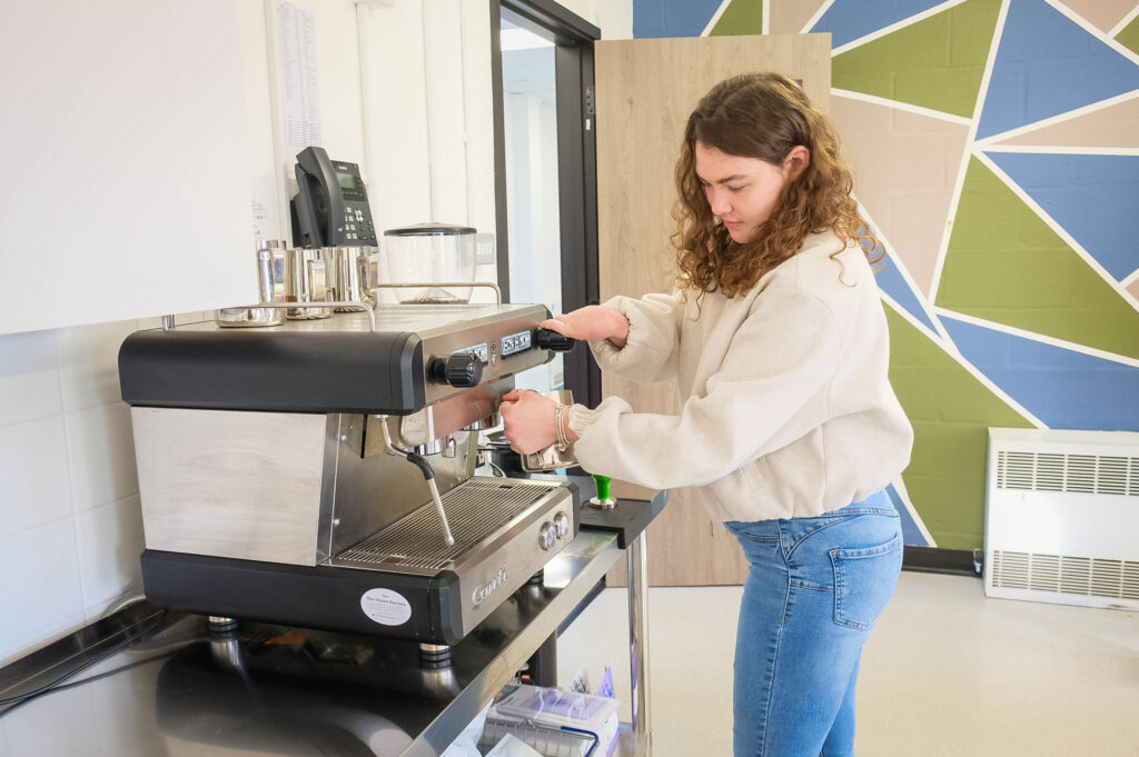 A young woman making a coffee on an espresso range