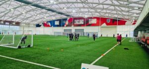 A football action shot, featuring learners from The Oaks Specialist College, at the indoor training centre of the England Football Team.