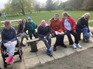 A group of young people enjoying a lunch at some picnic tables