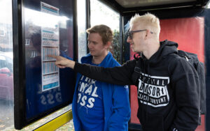 Two young men studying the bus timetable at a suburban bus stop