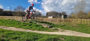 A young man on a mountain bike, following a wooden assault course