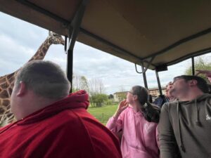 Three young people getting a close up view of a giraffe at a zoo