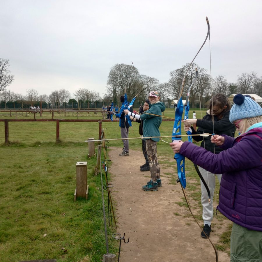 A group of young adults preparing to use a bow and arrow